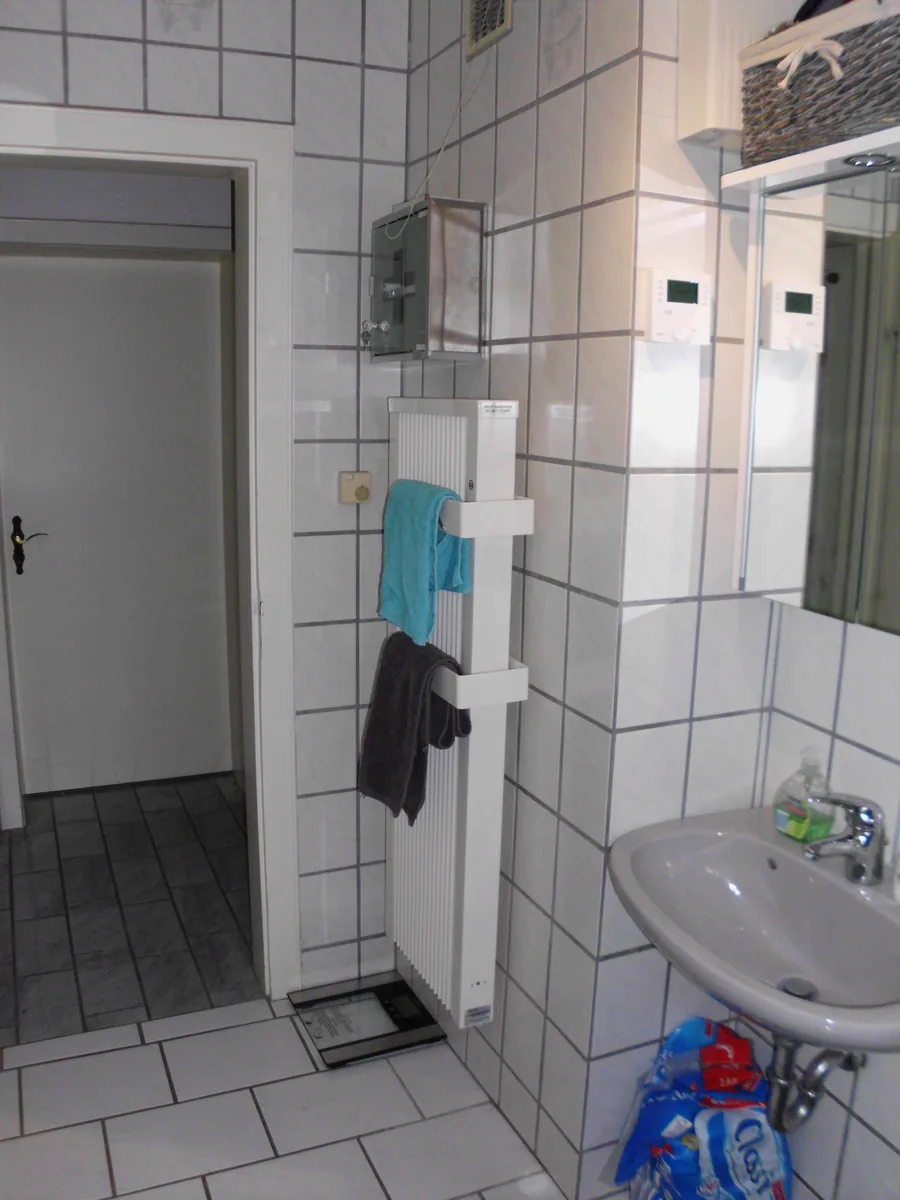 Schlanker weißer Badheizkörper mit Handtüchern in einem hellen Badezimmer