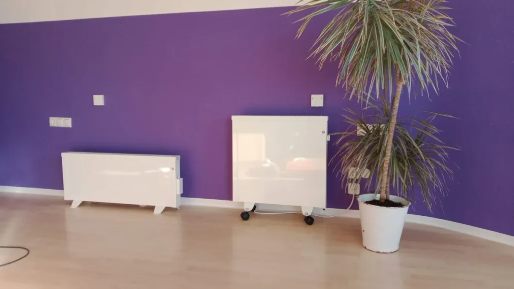 Zwei verschiedene Elektroheizungen vor einer violetten Wand in einem hellen Raum
