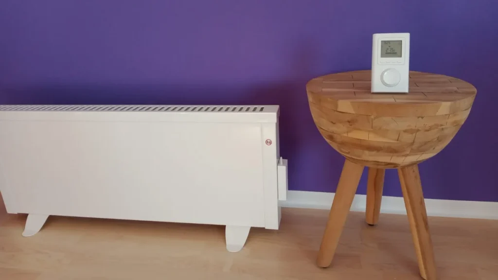 Mobile Elektroheizung vor einer violetten Wand neben einer großen Pflanze